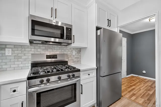 a kitchen with stainless steel appliances white cabinets a stove and a microwave