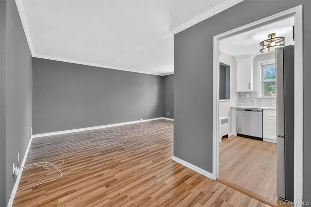 a view of a hallway view with wooden floor and a kitchen space