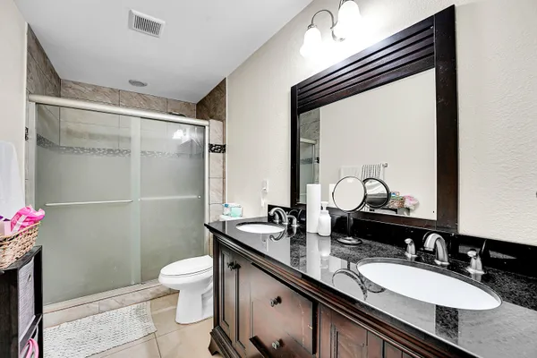 a bathroom with a granite countertop sink a toilet a mirror and shower