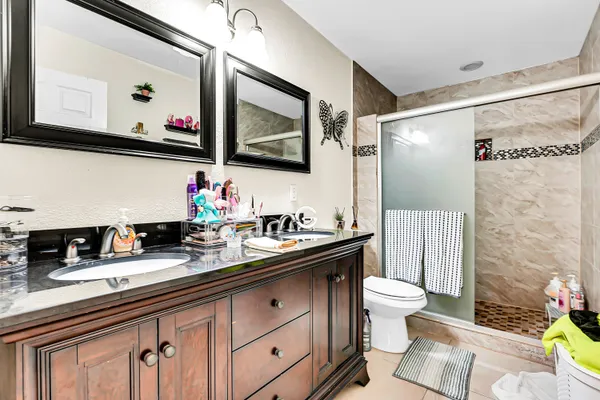 a bathroom with a granite countertop sink mirror vanity and toilet