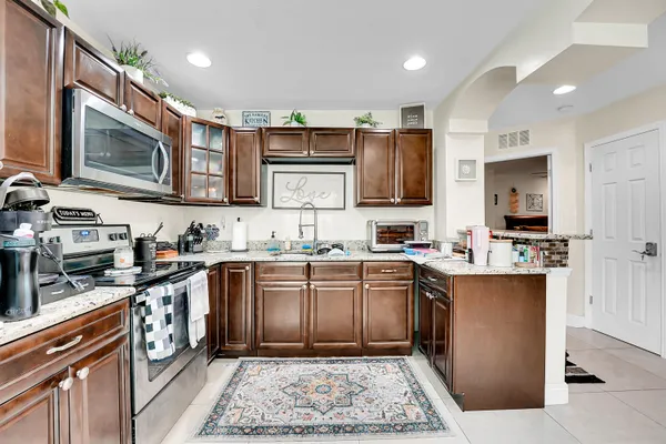 a kitchen with stainless steel appliances granite countertop a stove top oven a sink dishwasher a microwave oven and a refrigerator with wooden cabinets