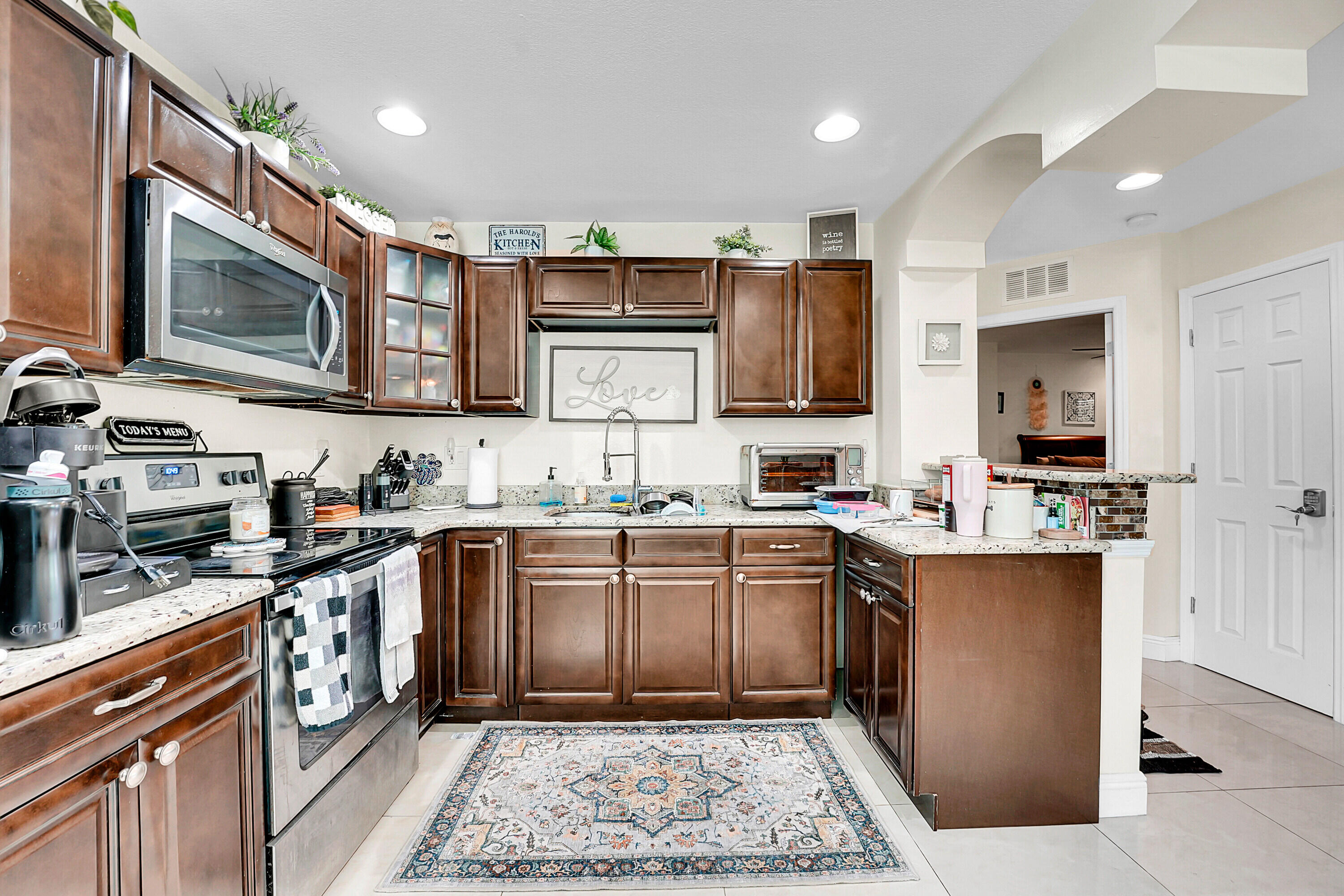 2856 Harson Way Fort Pierce, FL 34946 - Photo 18 of 37 a kitchen with stainless steel appliances granite countertop a stove top oven a sink dishwasher a microwave oven and a refrigerator with wooden cabinets