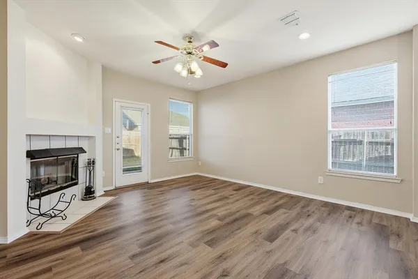 an empty room with wooden floor fan and windows