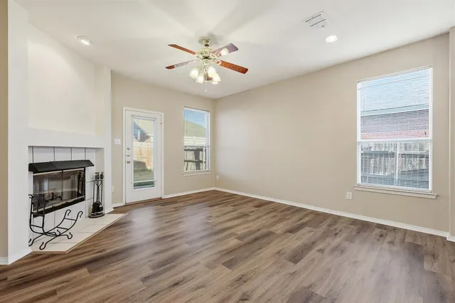 an empty room with wooden floor fan and windows