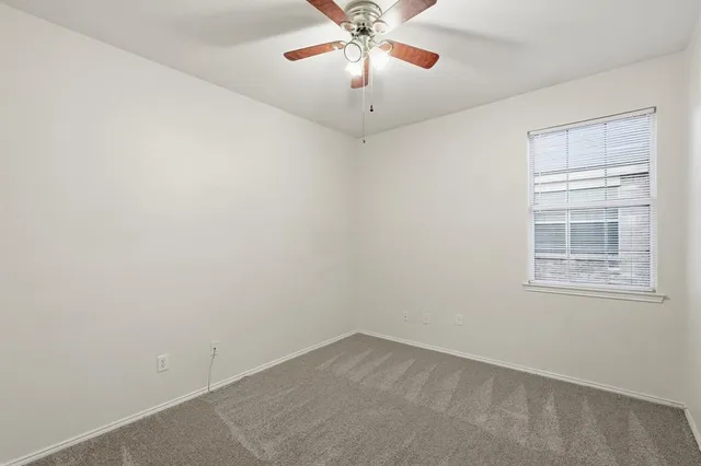 an empty room with a chandelier fan and windows