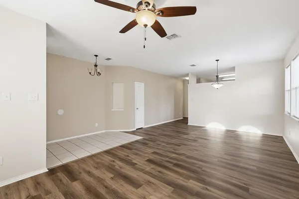 an empty room with wooden floor ceiling fan and windows