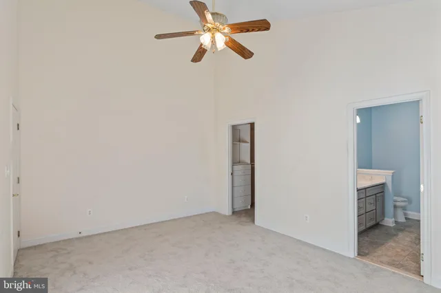 a view of an empty room and chandelier fan
