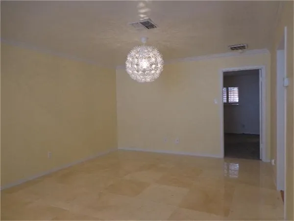 an empty room with a chandelier fan and wooden floor
