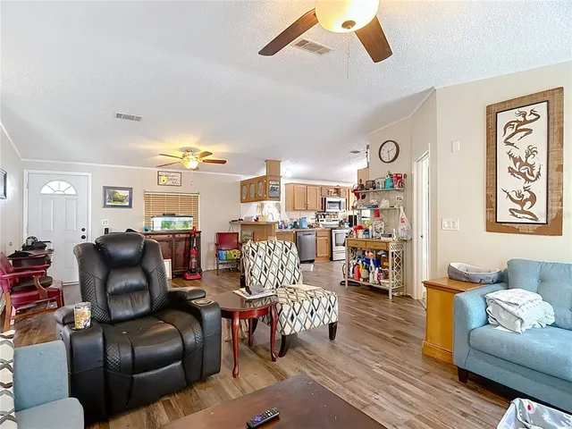 a kitchen with stainless steel appliances granite countertop a stove top oven a sink dishwasher a dining table and chairs with wooden floor