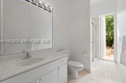 12982 Southwest 27th Street Miami, FL 33175 - Photo 30 of 43 a bathroom with a granite countertop sink a toilet and a large mirror