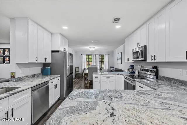 a kitchen with granite countertop kitchen island white cabinets and stainless steel appliances