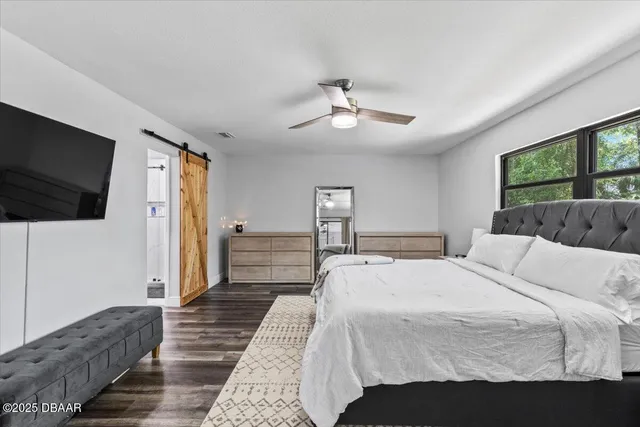 a bedroom with a large bed a flat tv screen and a couch