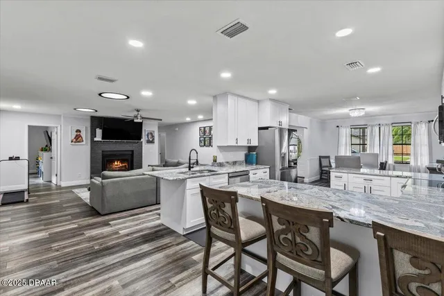 a kitchen with stainless steel appliances granite countertop a stove top oven a sink dishwasher a dining table and chairs with wooden floor