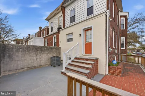 a view of a house with a barbeque and wooden stairs