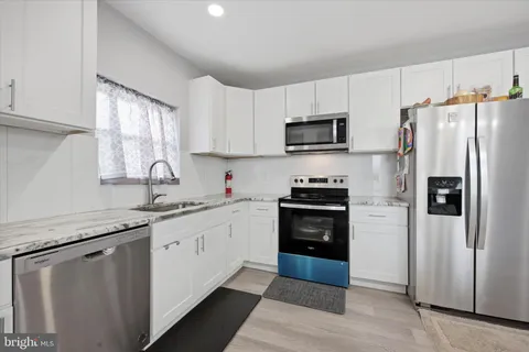 a kitchen with granite countertop a refrigerator stove and sink