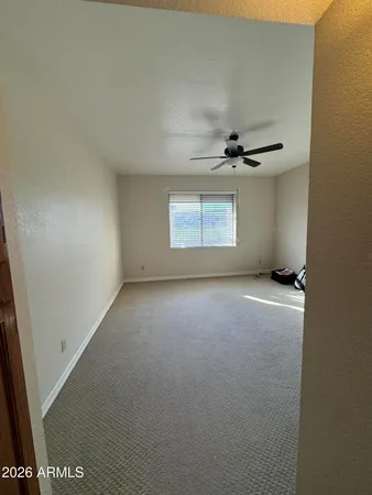 an empty room with a ceiling fan and window
