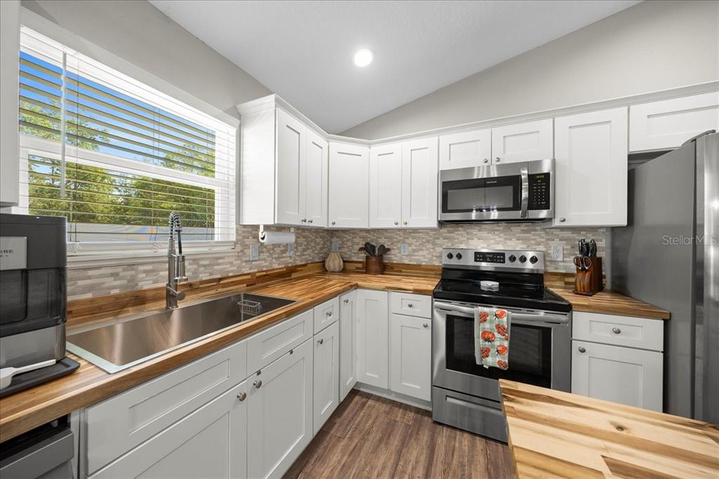 13 Teak Loop Place Ocala, FL 34472 - Photo 5 of 36 a kitchen with stainless steel appliances a sink dishwasher a stove top oven a refrigerator with wooden floor and cabinets