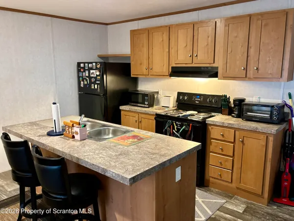 a open kitchen with stainless steel appliances granite countertop a refrigerator a sink dishwasher a dining table and chairs with wooden floor