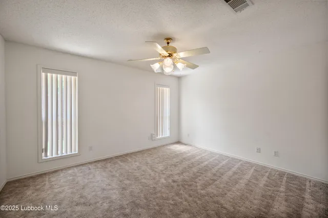a view of an empty room with chandelier fan