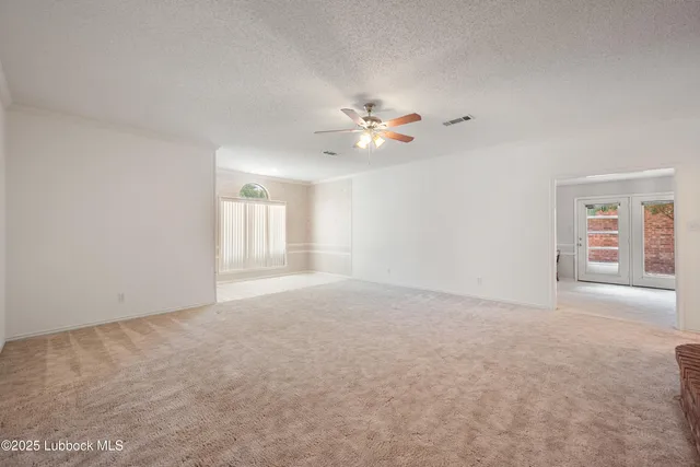 an empty room with chandelier fan and windows