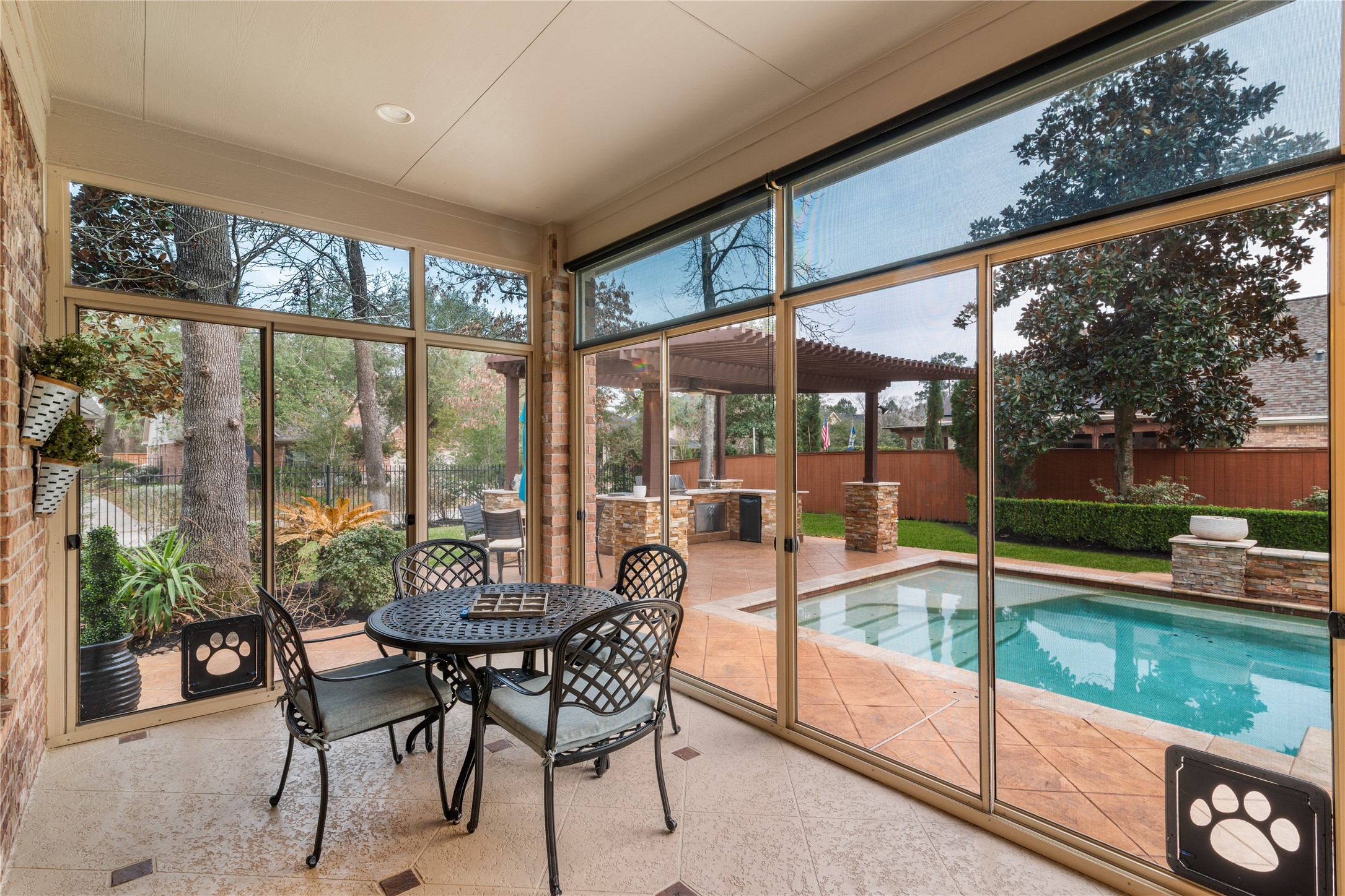 155 South Arrow Canyon Circle Spring, TX 77389 - Photo 33 of 49 This setting showcases a bright, screened-in patio that serves as a seamless transition to a lush, well-maintained backyard. The outdoor space features a swimming pool, a pergola with a built-in grill area, and lush landscaping, offering an ideal setting for relaxation and entertainment.