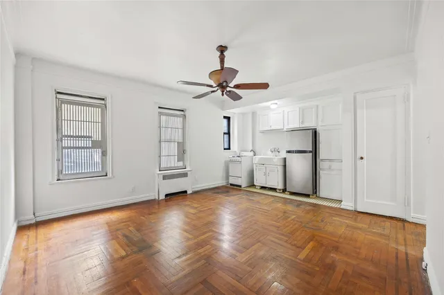 a view of empty room with wooden floor and ceiling fan