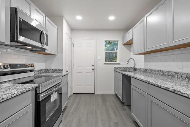 a kitchen with stainless steel appliances granite countertop a sink and a stove top oven