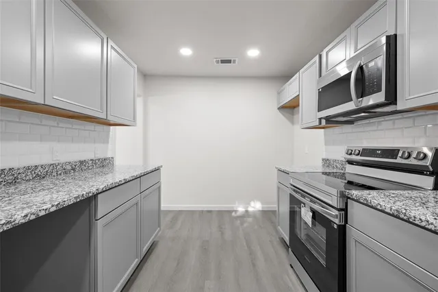 a kitchen with stainless steel appliances granite countertop a sink a stove and a microwave oven with cabinets