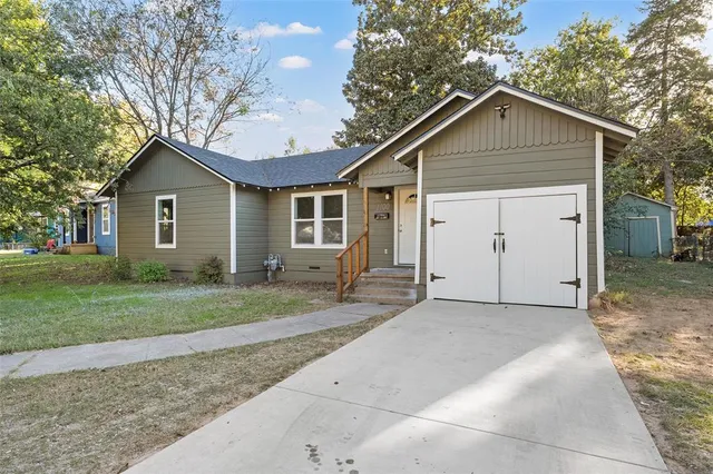 a view of house with a yard and large tree