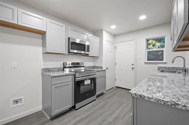a kitchen with stainless steel appliances granite countertop a stove a sink and a microwave