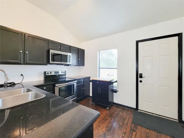 a kitchen with stainless steel appliances granite countertop a sink stove microwave and refrigerator
