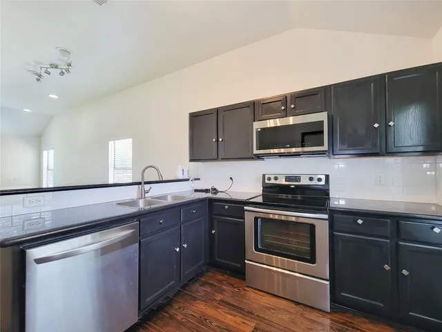 a kitchen with stainless steel appliances granite countertop a sink a stove top oven and wooden cabinets