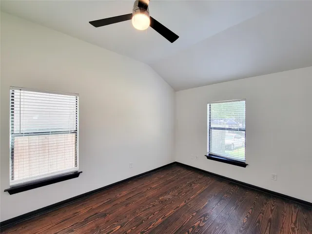 an empty room with wooden floor chandelier fan and windows