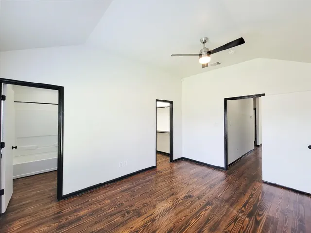 an empty room with wooden floor and a ceiling fan