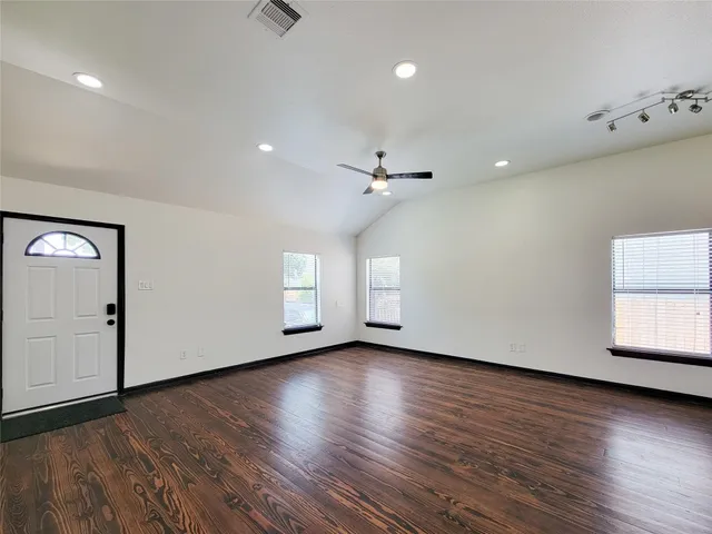a view of an empty room with wooden floor and a window