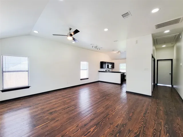 an empty room with wooden floor chandelier and windows