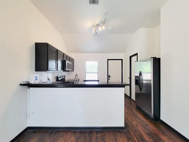 a large white kitchen with kitchen island a counter top space and stainless steel appliances