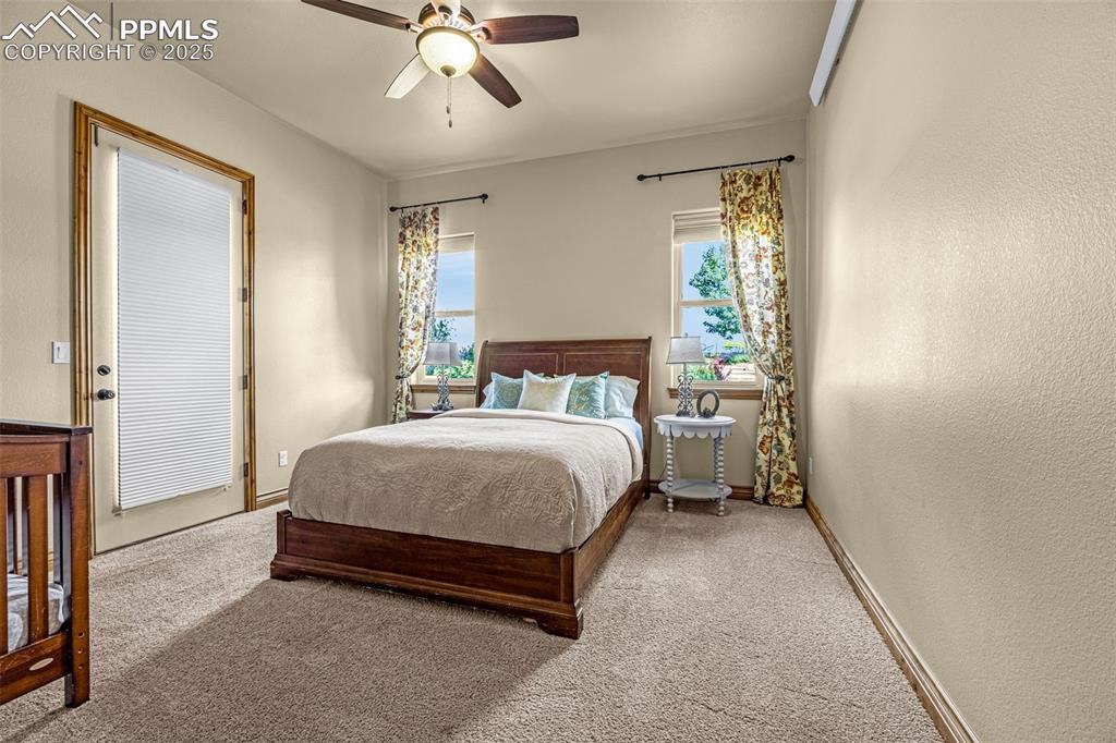 11784 Spruce Mountain Road Larkspur, CO 80118 - Photo 32 of 49 a spacious bedroom with a bed and a chandelier
