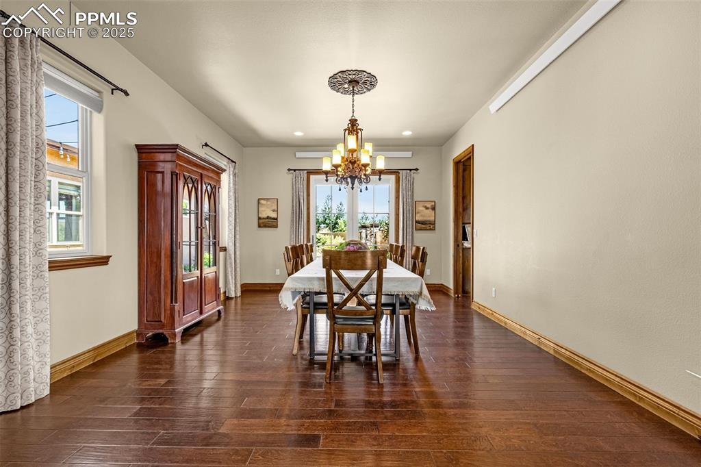 11784 Spruce Mountain Road Larkspur, CO 80118 - Photo 6 of 49 a dining room with wooden floor a chandelier a glass table and chairs