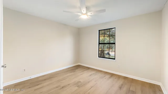 an empty room with a window and ceiling fan