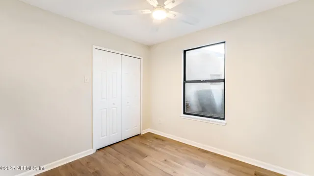 an empty room with wooden floor closet and windows