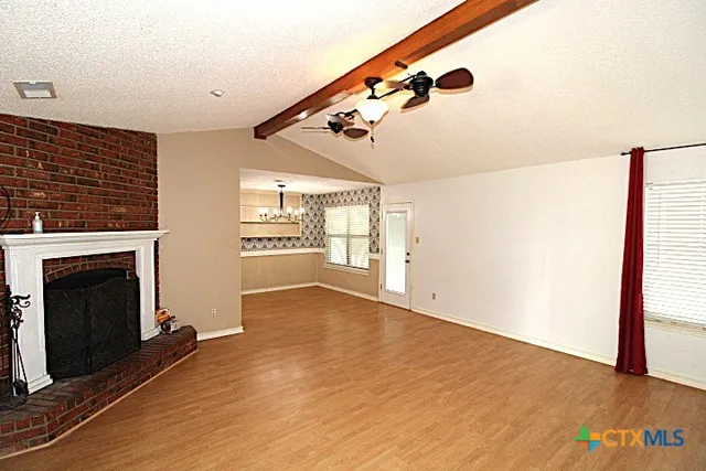 a view of an empty room with a fireplace and wooden floor