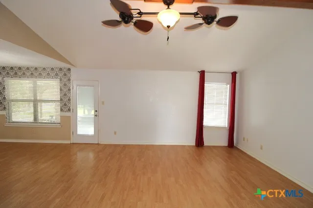 an empty room with windows and chandelier fan