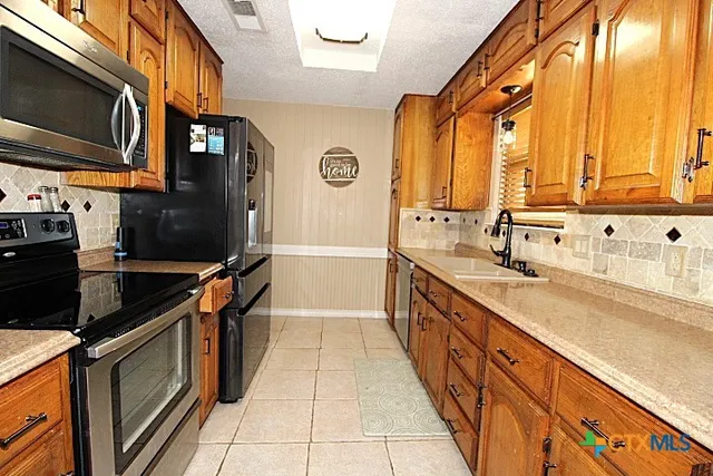 a kitchen with stainless steel appliances a sink stove and cabinets