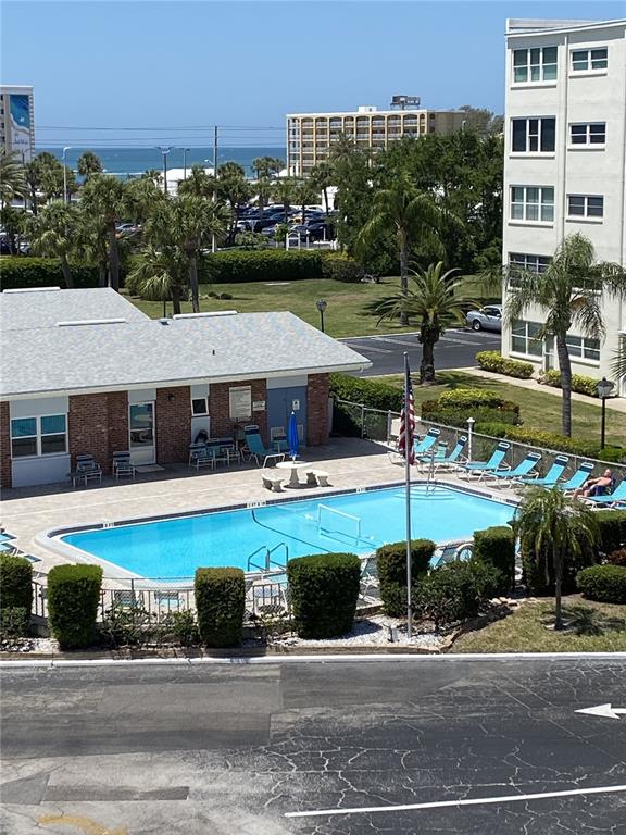5555 Gulf Boulevard, Unit 104 St. Pete Beach, FL 33706 - Photo 30 of 35 a view of a patio with swimming pool and table and chairs under an umbrella