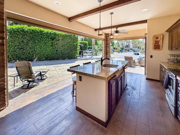 a kitchen with stainless steel appliances kitchen island granite countertop a refrigerator a stove top oven and a dining table with wooden floor