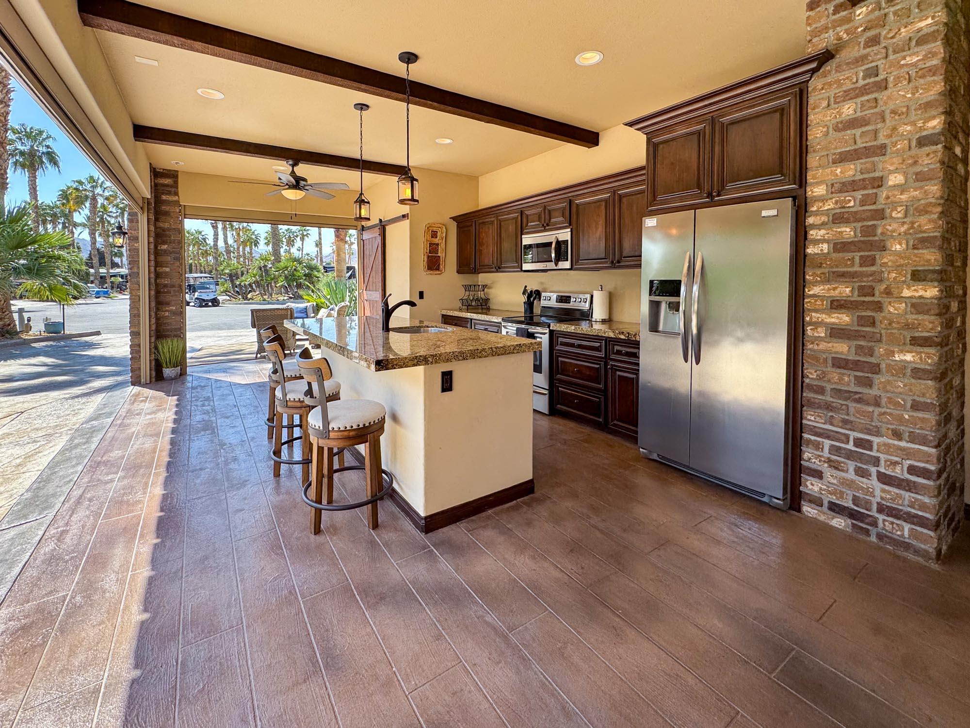 80394 Ave 48, Unit 116 Indio, CA 92201 - Photo 22 of 26 a kitchen with stainless steel appliances kitchen island granite countertop a refrigerator a stove top oven and a dining table with wooden floor