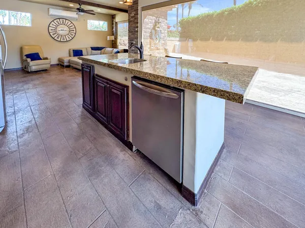 a living room with stainless steel appliances granite countertop a sink dishwasher stove and cabinets