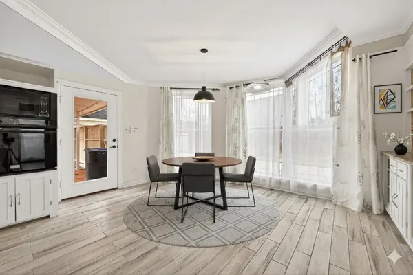 a dining room with wooden floor a chandelier a wooden table and chairs