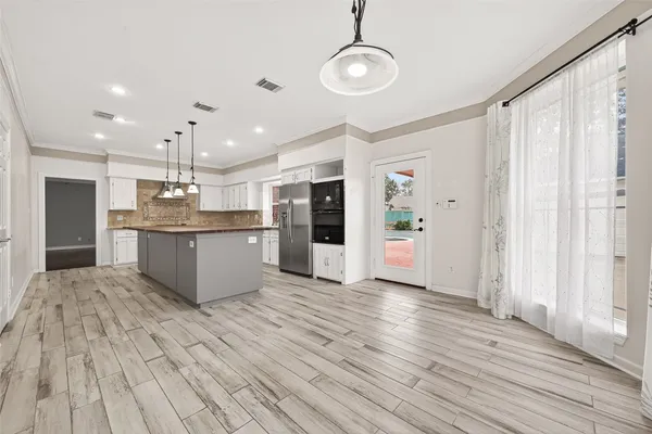 a large kitchen with stainless steel appliances granite countertop a lot of counter space and wooden floors